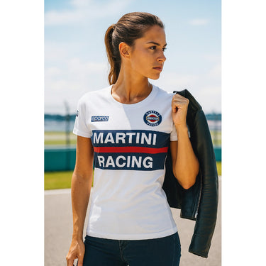 Woman wearing a white 'Martini Racing' shirt outdoors with a clear sky.